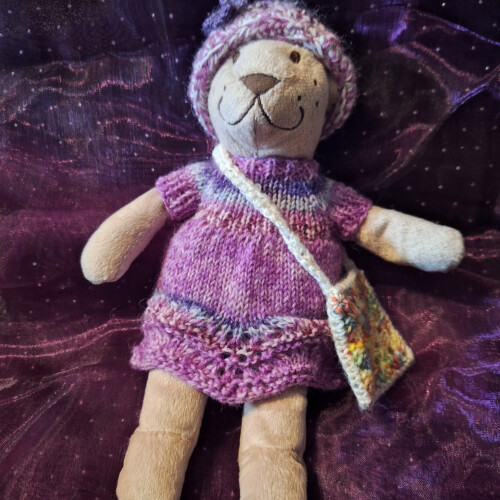 En nalle iklädd stickad klänning, hatt och handväska