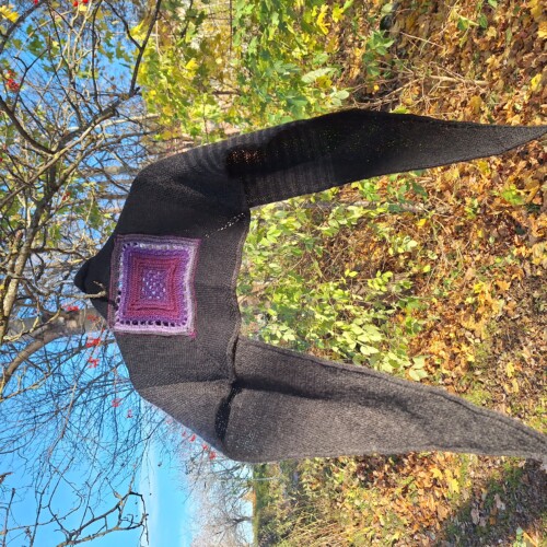 En stickad sjal hänger från ett träd